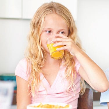 Child drinking orange juice, a mixable option to administer Vyvanse® (lisdexamfetamine dimesylate).